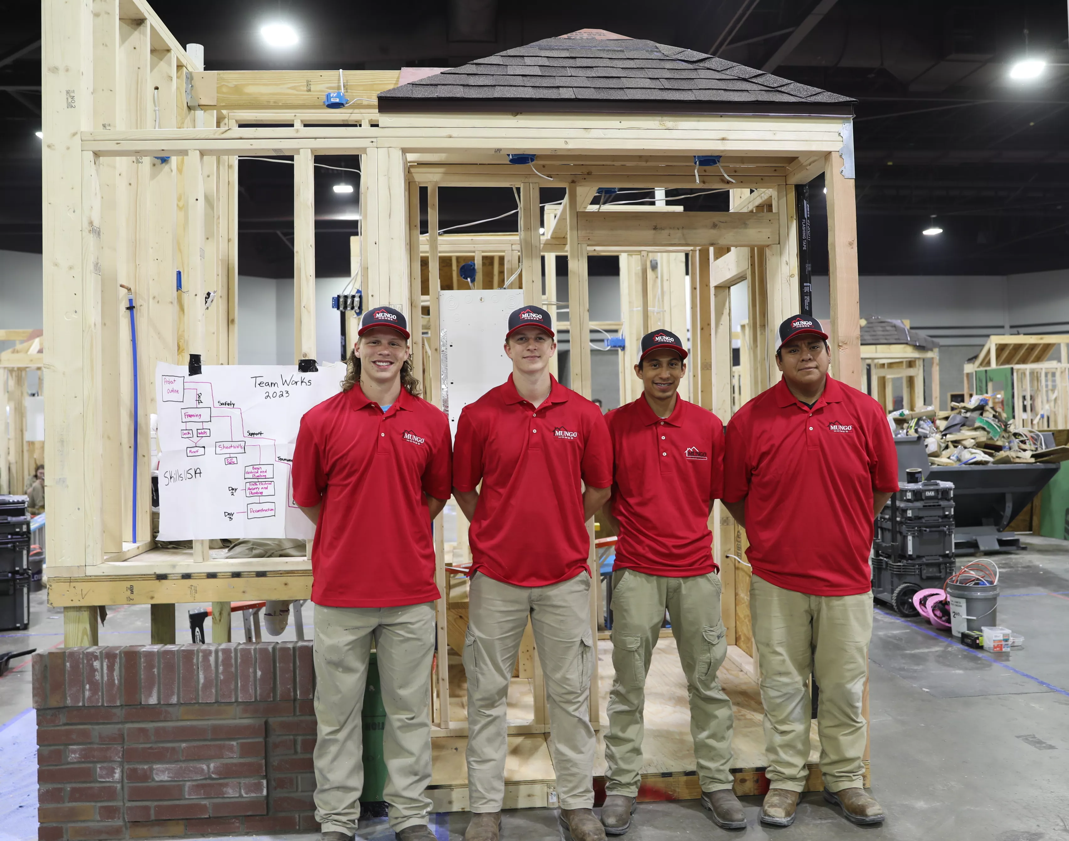 Cameron Drake, Ethan Reynolds, William Rodriguez, and Angel Mendoza standing together and smiling in front of house frame