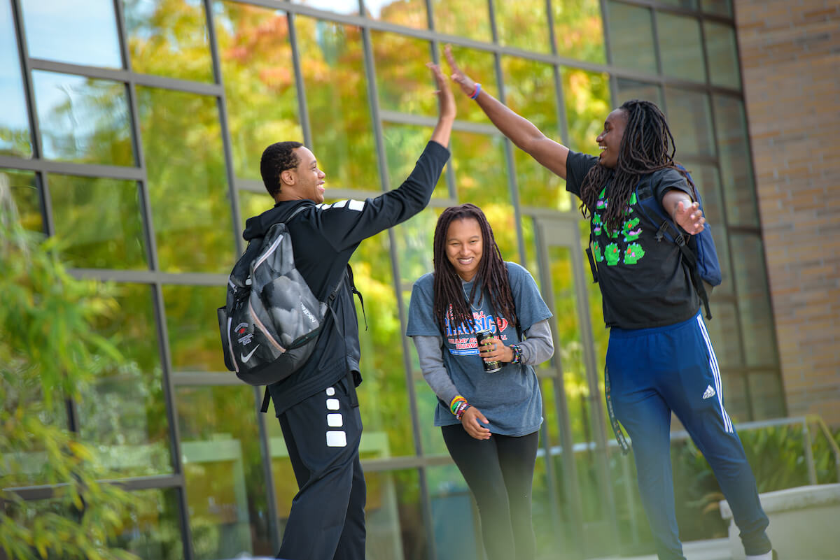 "students high-five on campus"