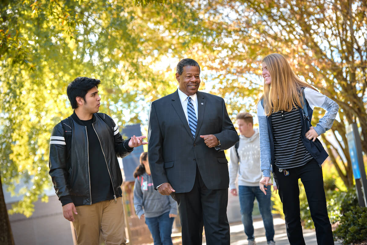 MTC President Ron Rhames walking with students on campus.