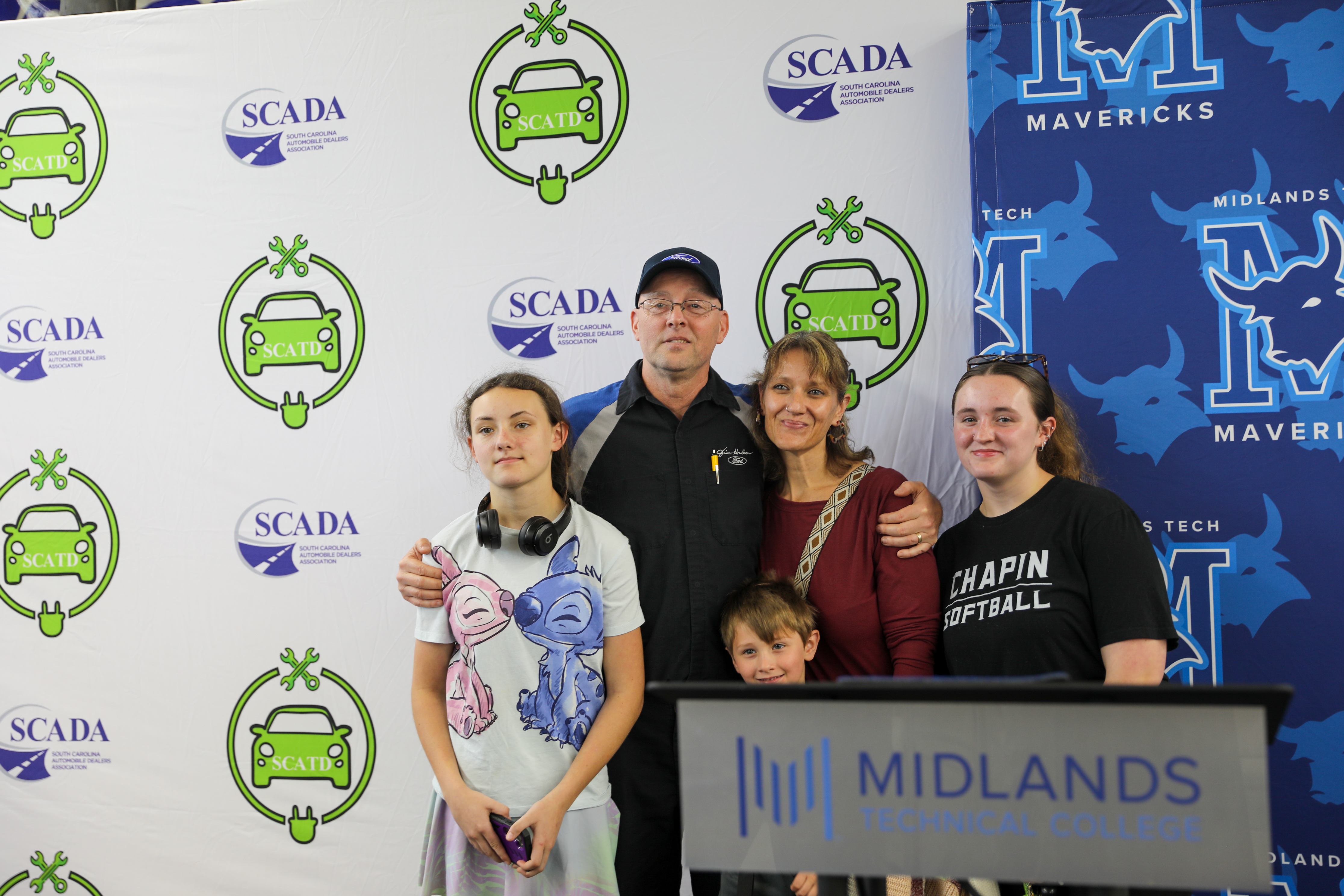 Image of one apprentice with his family, posing and smiling for a photo.