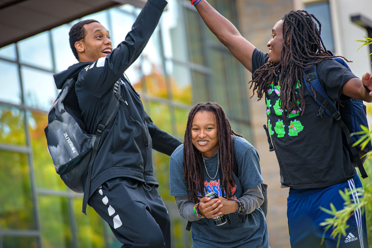 students high five on campus.