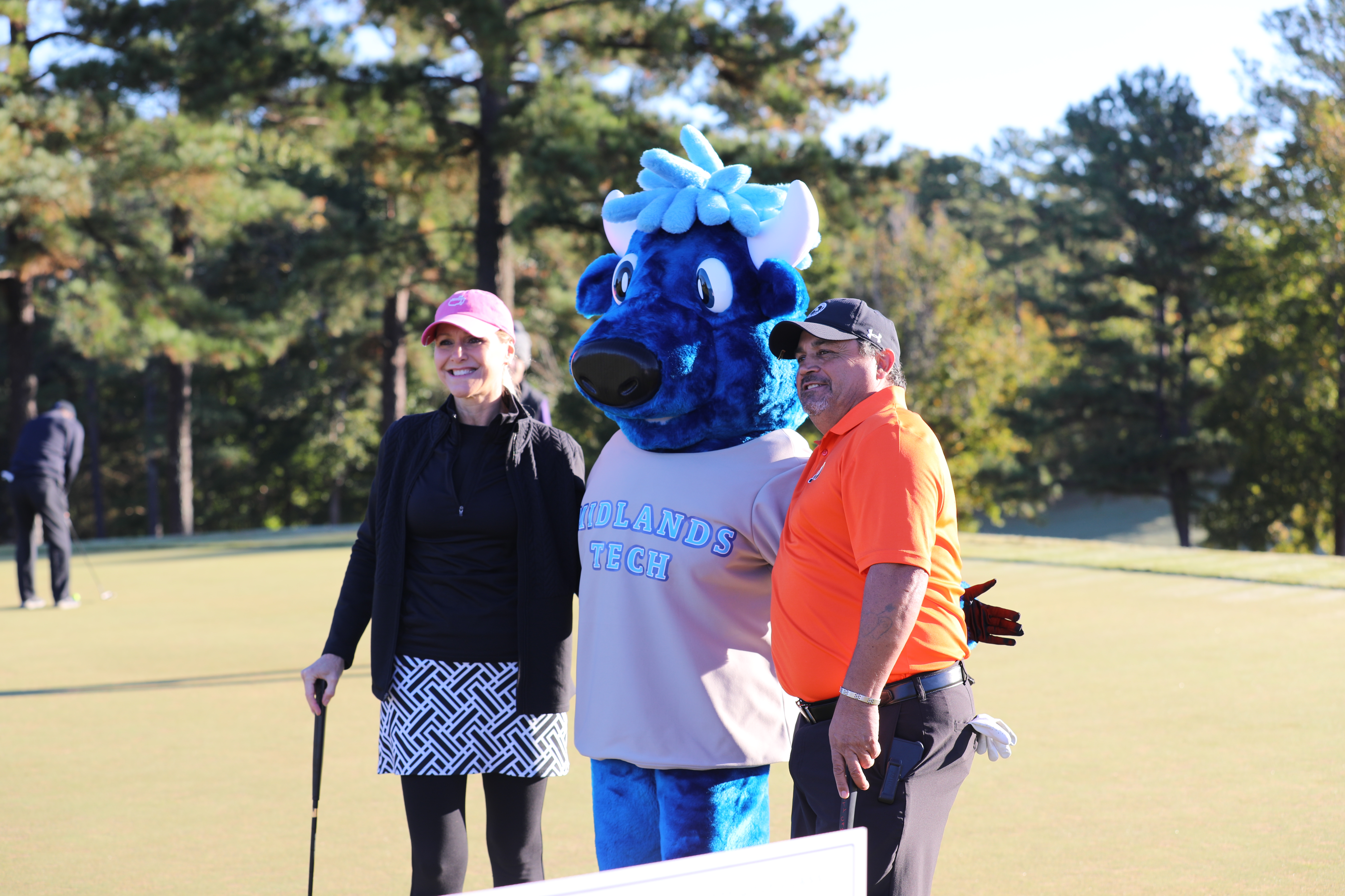 MTC Mascot Mav poses with golf tournament participants. 