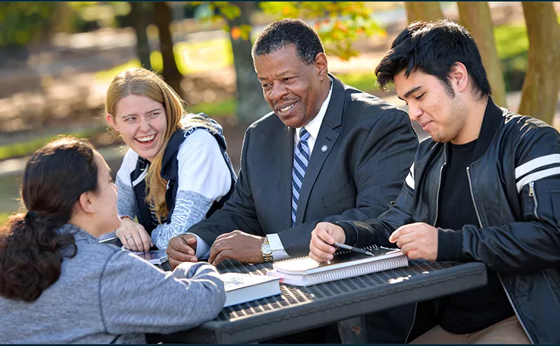 Dr. Rhames sitting at table with three students