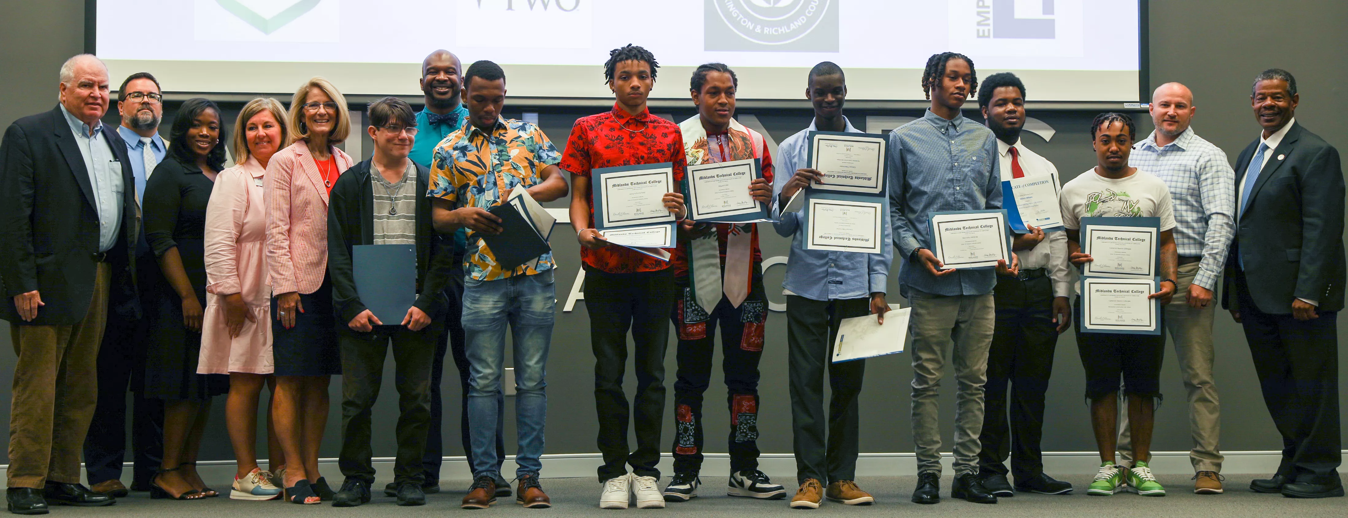 BOOM graduates stand with their certificates alongside MTC and local school district leaders.