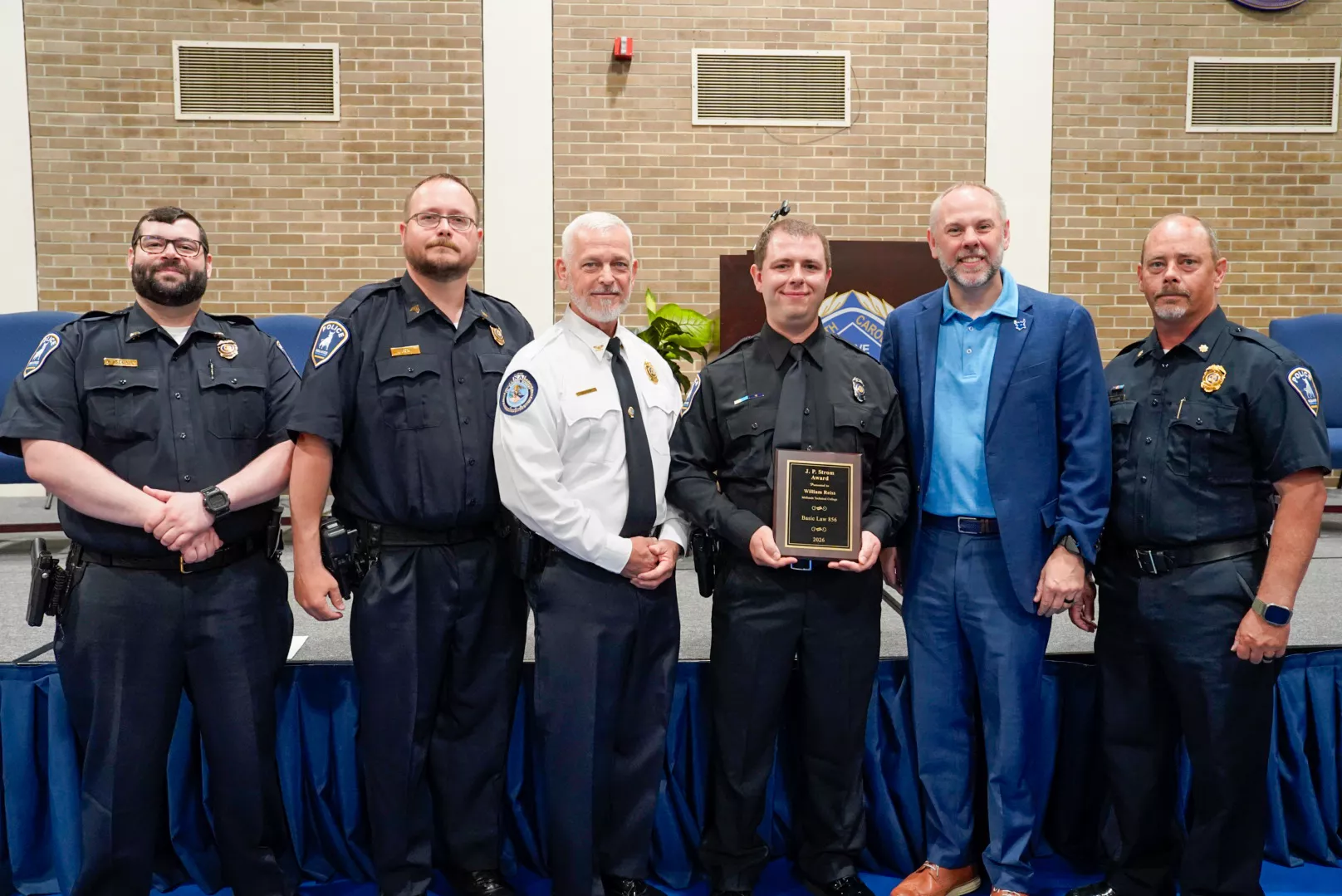 William Reiss holding his award beside coworkers.